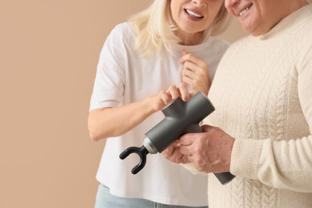 Mature couple with percussive massager on beige background, closeupの写真素材