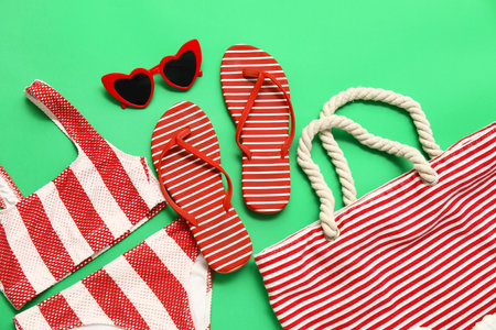 Flip flops with bag, sunglasses and swimsuit on green backgroundの写真素材