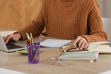 Female tutor with laptop and notebooks giving online lesson at home, closeupの写真素材
