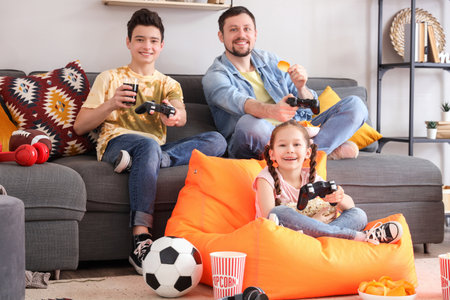 Little children and their father with snacks playing video game at homeの写真素材
