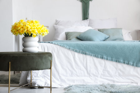Vase with daffodils on green pouf in bedroomの写真素材