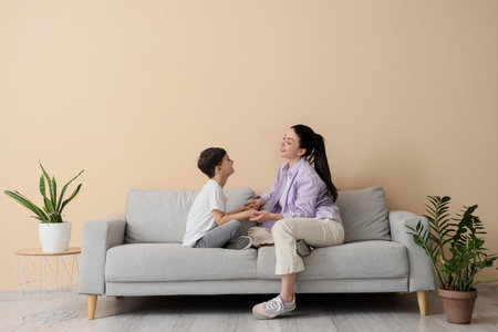 Mother with her little son holding hands on sofa at homeの写真素材