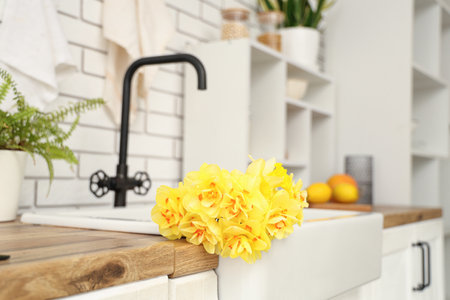 Beautiful bouquet of daffodils in sink in kitchenの写真素材