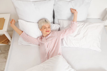 Young woman with short hair lying in bedroom, top viewの写真素材