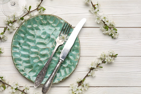 Beautiful table setting with blossoming branches on white wooden background