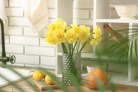 Beautiful bouquet of daffodils in interior of modern kitchenの写真素材