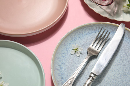Beautiful table setting with blossoming flowers on pink background