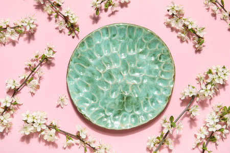 Beautiful plate with blossoming branches on pink backgroundの写真素材