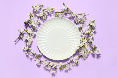 Beautiful plate with blossoming branches on lilac backgroundの写真素材