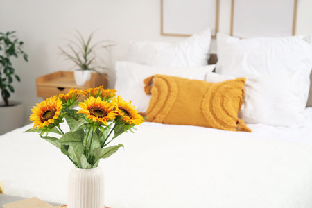 Interior of light bedroom with cozy bed and beautiful sunflowers, closeupの写真素材
