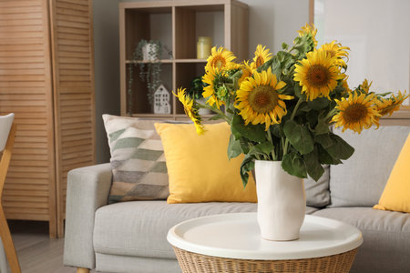 Stylish living room with gray sofa and vase of sunflowers bouquet on coffee tableの写真素材