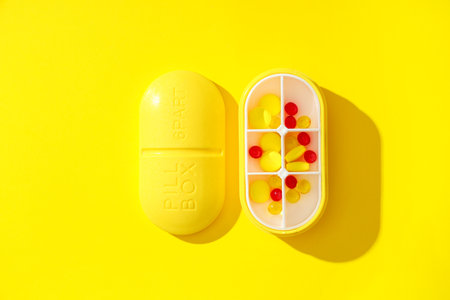 Plastic container with pills on yellow background. Top viewの写真素材