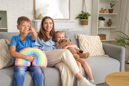 Cute little children with their mother watching cartoons on TV at homeの写真素材