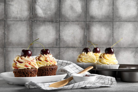 Plate and baking mold with sweet cherry cupcakes on gray table