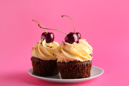 Plate with sweet cherry cupcakes on pink backgroundの写真素材