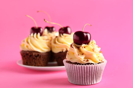 Plate with sweet cherry cupcakes on pink backgroundの写真素材