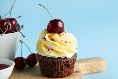 Wooden board with sweet cherry cupcake and berries on blue backgroundの写真素材