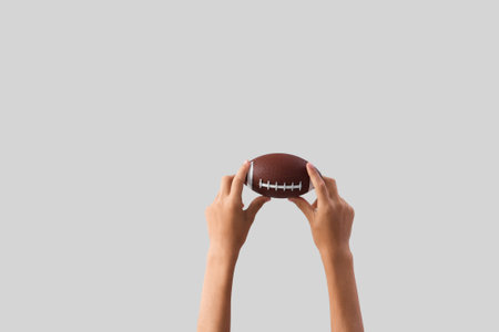 Child with small rugby ball on light background