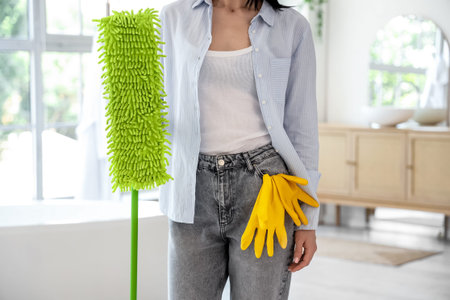 Young woman with mop and gloves at home, closeup