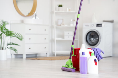Mop with bucket and different cleaning supplies on floor at homeの写真素材