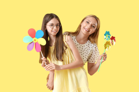 Teenage girl and her mother with toy windmills on yellow backgroundの写真素材