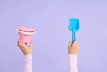 Child with beach toys on lilac background
