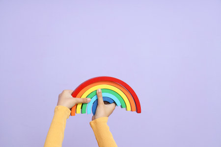 Child with toy rainbow on lilac backgroundの写真素材