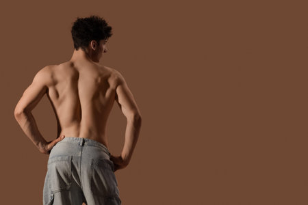 Muscular young man on brown background, back view