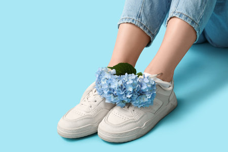 Legs of young woman in white socks with hydrangea flowers on blue backgroundの写真素材