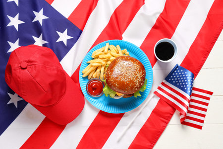 Tasty burger with French fries, cola, red and flag of USA on white wooden background. American Independence Day celebrationの写真素材