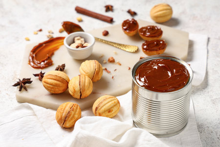 Board with tasty walnut shaped cookies, boiled condensed milk and ingredients on white grunge tableの写真素材