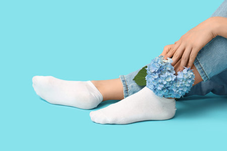 Legs of young woman in white socks with hydrangea flowers on blue backgroundの写真素材