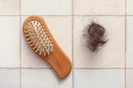 Brush with clump of hair on light background. Hair loss problem