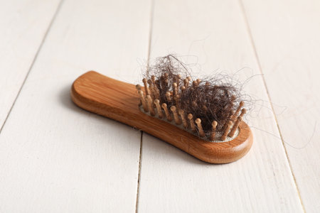 Brush with clump of hair on light wooden background. Hair loss problemの写真素材