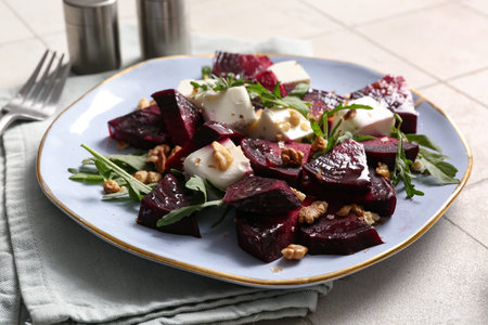Plate of fresh salad with beet and walnut on white tile backgroundの写真素材