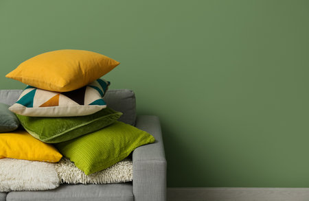 Stack of cushions on gray sofa near green wall in roomの写真素材