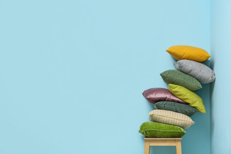 Stack of cushions on chair near blue wall in roomの写真素材