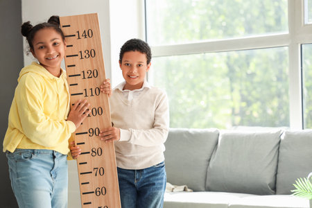Little African-American children with stadiometer at homeの写真素材
