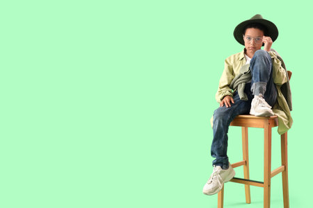 Little African-American boy in adult clothes sitting on green backgroundの写真素材