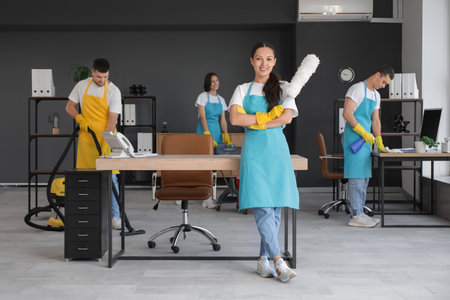 Female Asian janitor with pp-duster in officeの写真素材