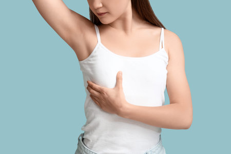 Young woman checking her breast on blue background