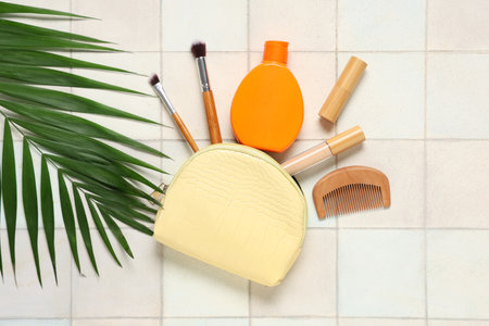 Beautiful composition with cosmetic bag, sunscreen and decorative cosmetics on tile backgroundの写真素材
