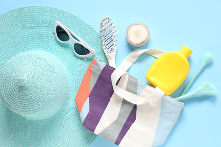 Beautiful composition with cosmetic bag, hat and accessories on blue backgroundの写真素材