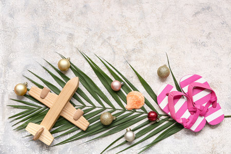 Wooden airplane, kid's flip-flops and palm branch with Christmas balls on white grunge background. Top viewの写真素材