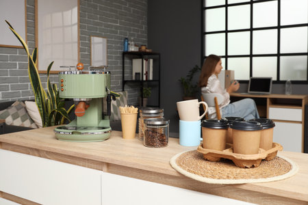 Coffee machine with stir sticks, jars and cups on table in officeの写真素材