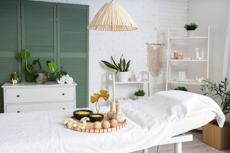 Interior of light spa salon with massage couch, shelf units and plantsの写真素材