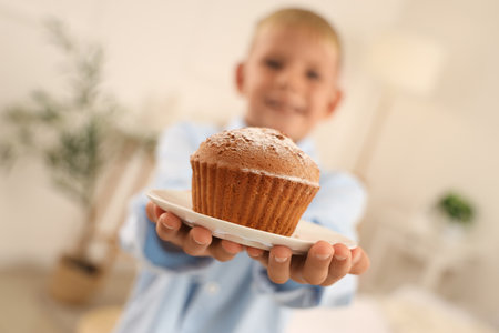 Little boy with tasty muffin in bedroom, closeupの写真素材