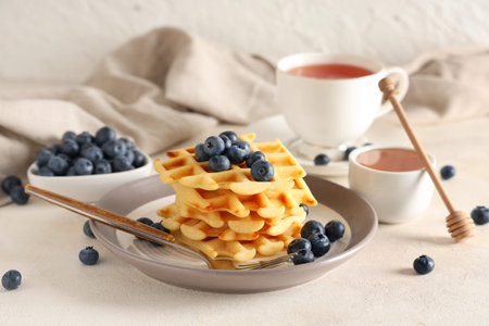 Delicious Belgian waffles with blueberries in plate on table against white backgroundの写真素材