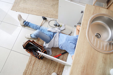 Male plumber fixing sink in kitchen, top viewの写真素材