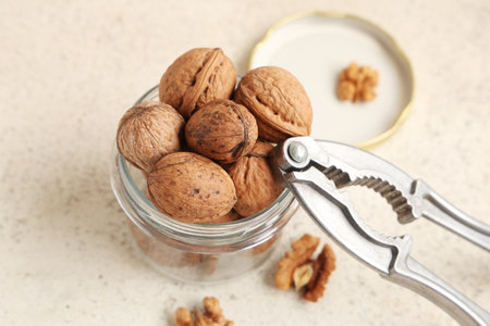 Jar with tasty walnuts and nutcracker on white backgroundの写真素材